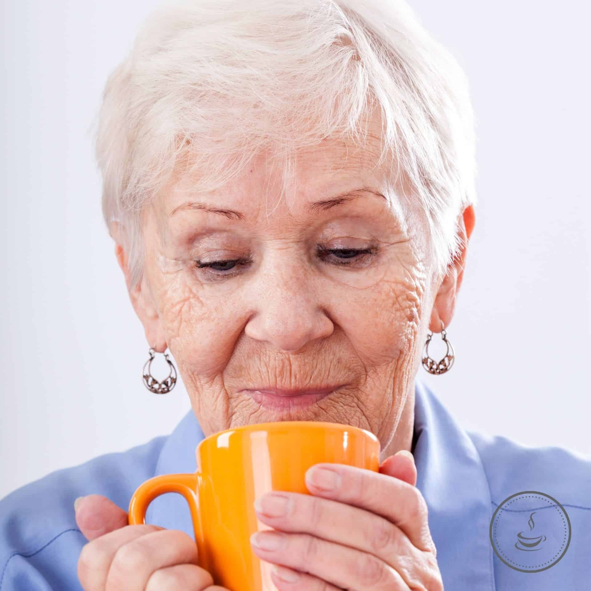 Elderly woman savoring nostalgia with her favorite orange mug in a cozy moment.