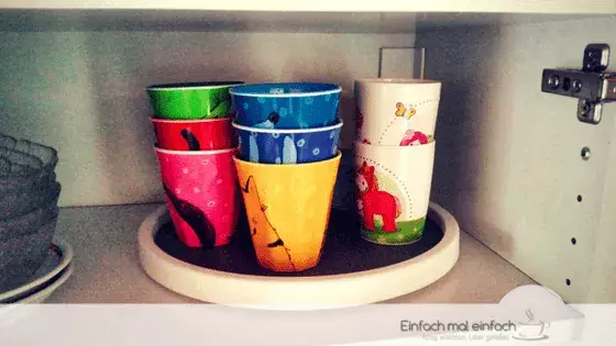 Simple space-saving hacks 4 Colorful kids cups arranged on a Lazy Susan in a cupboard.