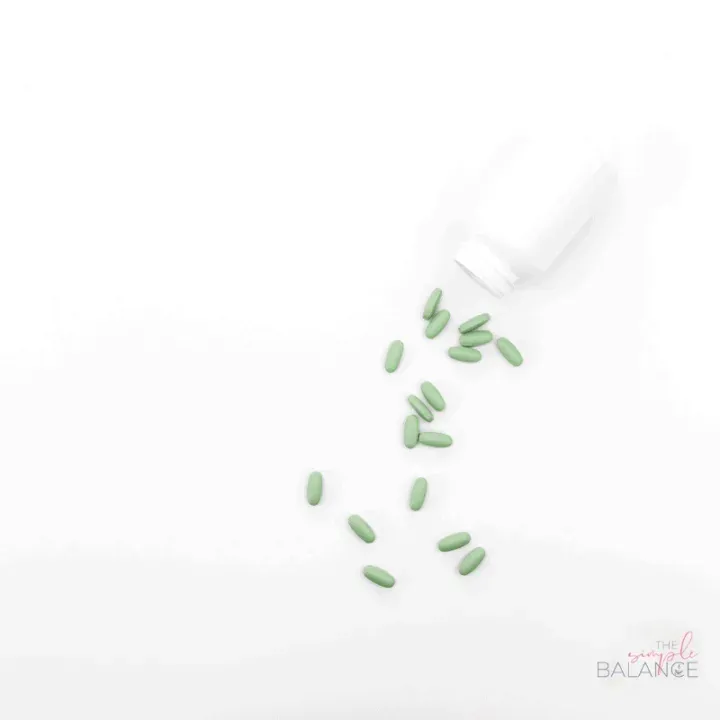 White pill bottle spilling green capsules, emphasizing wellness and healthy living.