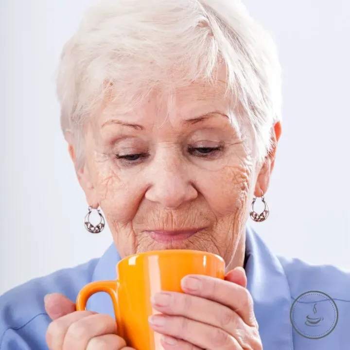 Elderly woman savoring nostalgia with her favorite orange mug in a cozy moment.